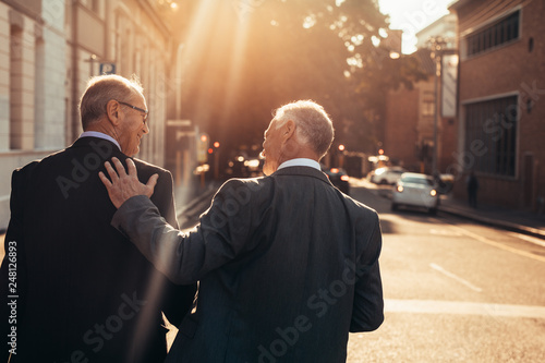 Two senior business people walking outdoors