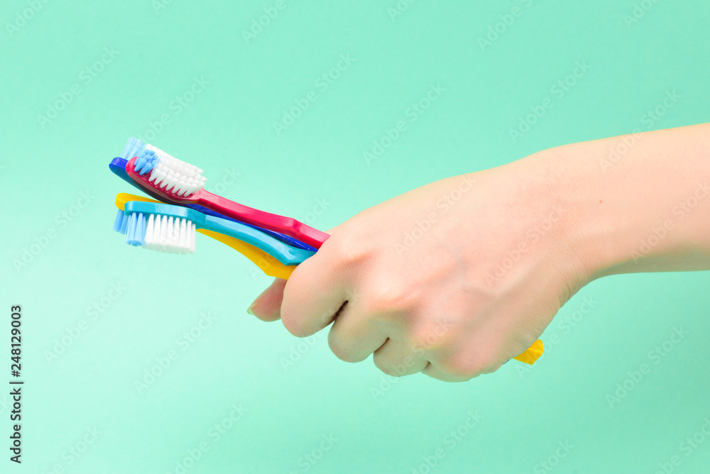 The woman holds toothbrushes in her hand on a green background. The woman holds toothbrushes in her hand on a green background.