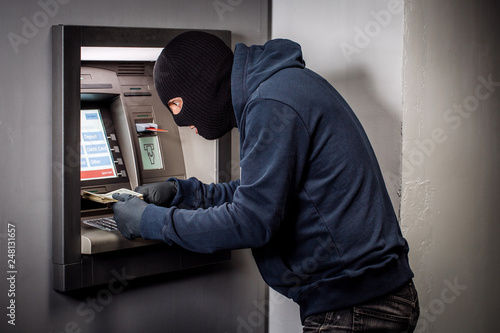 thief with crowbar opens the ATM.