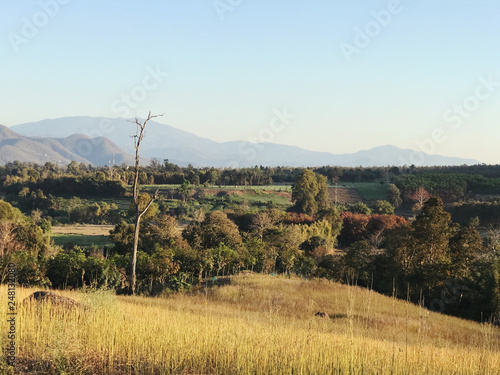 Authentic picturesque horizontal shot of rural landscape view with beautiful cloudy mountains and dry fields. Fresh air of colofrul winter in Thailand.