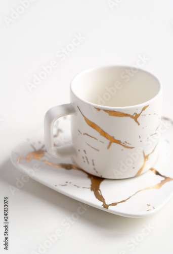 White mugs with a saucer. Cups for coffee and tea on a white background. Utensils for any holiday  luxury wedding  birthday or party. Style Japanese art of repair broken dishes  kintsugi. Gold streaks