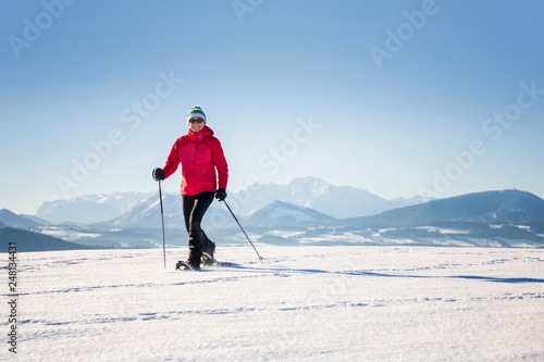 Snowshoeing - woman trekking in winter mountains