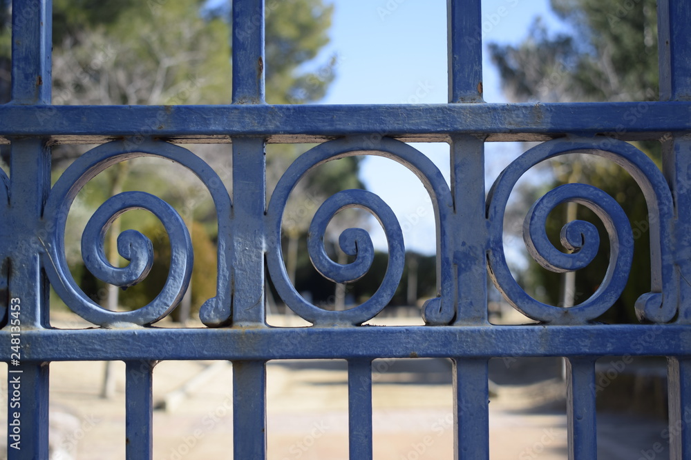 Verja en forma de espiral azul, de hierro, de fondo parque Verja en forma de espiral azul, de hierro, de fondo parque