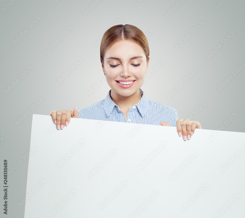 Young smiling woman showing white empty paper banner background with copy space. Happy woman portrait, business and education concept Young smiling woman showing white empty paper banner background with copy space. Happy woman portrait, business and education concept