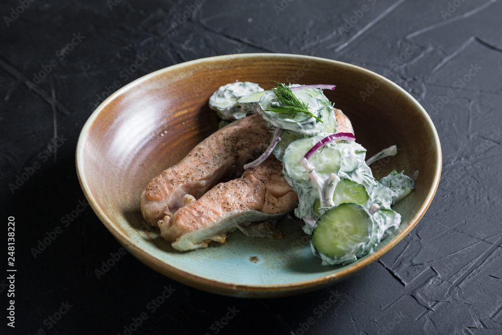 A piece of grilled salmon with cucumbers and Greek yogurt A piece of grilled salmon with cucumbers and Greek yogurt