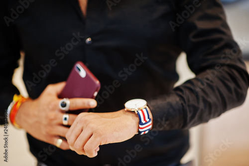 Hands of indian man posed with mobile phone and looking at his watches.