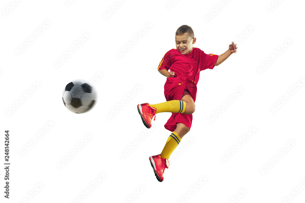Fototapeta premium Young boy kicks the soccer ball. Isolated photo on white background. Football player in motion at studio. Fit jumping boy in action, jump, movement at game.