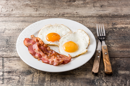 Fried eggs and bacon for breakfast on wooden table