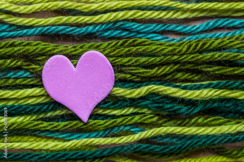 Coeur rose sur des fils de laine verts