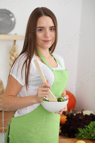 Young woman cooking in kitchen. Householding, tasty food and digital technology in lifestyle concepts photo