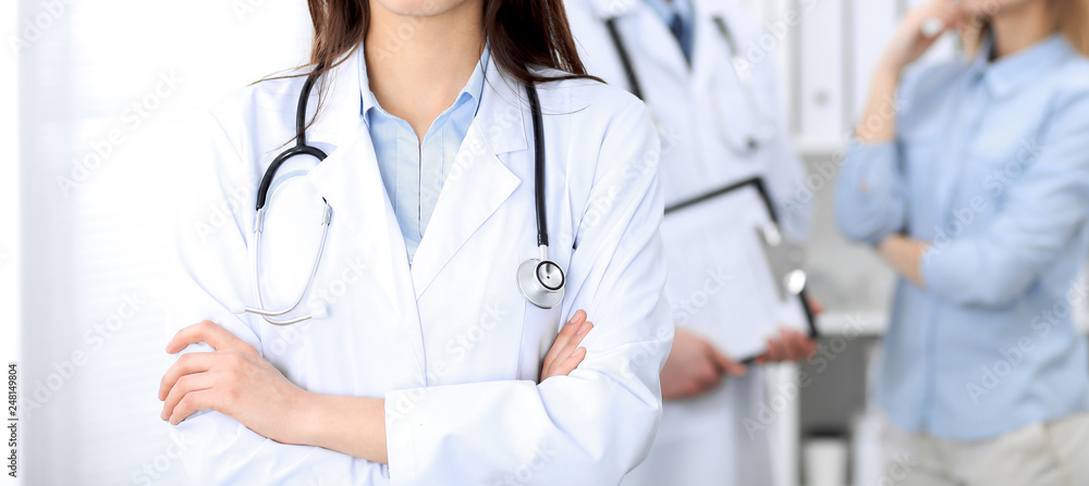 Female doctor with stethoscope standing upright with crossed arms, unknown physician at work. Medicine concept Female doctor with stethoscope standing upright with crossed arms, unknown physician at work. Medicine concept