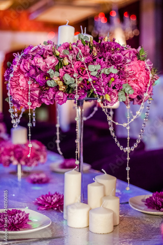 Wedding party table flowers and white candles on the table. Pink pions and wite chrysanthemums bouqet with shining decor