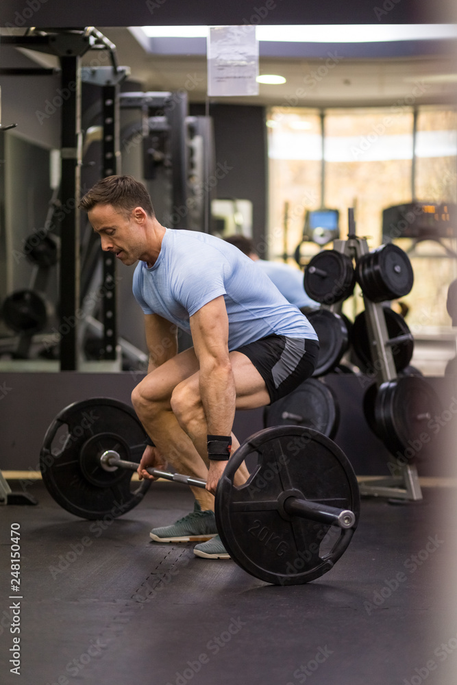 Image of a muscular man pulling a heavy barbell at the gym. Image of a muscular man pulling a heavy barbell at the gym.