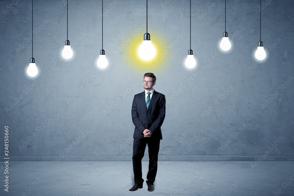 Fototapeta premium Handsome businessman in an empty space with bulbs above and uninspired face 