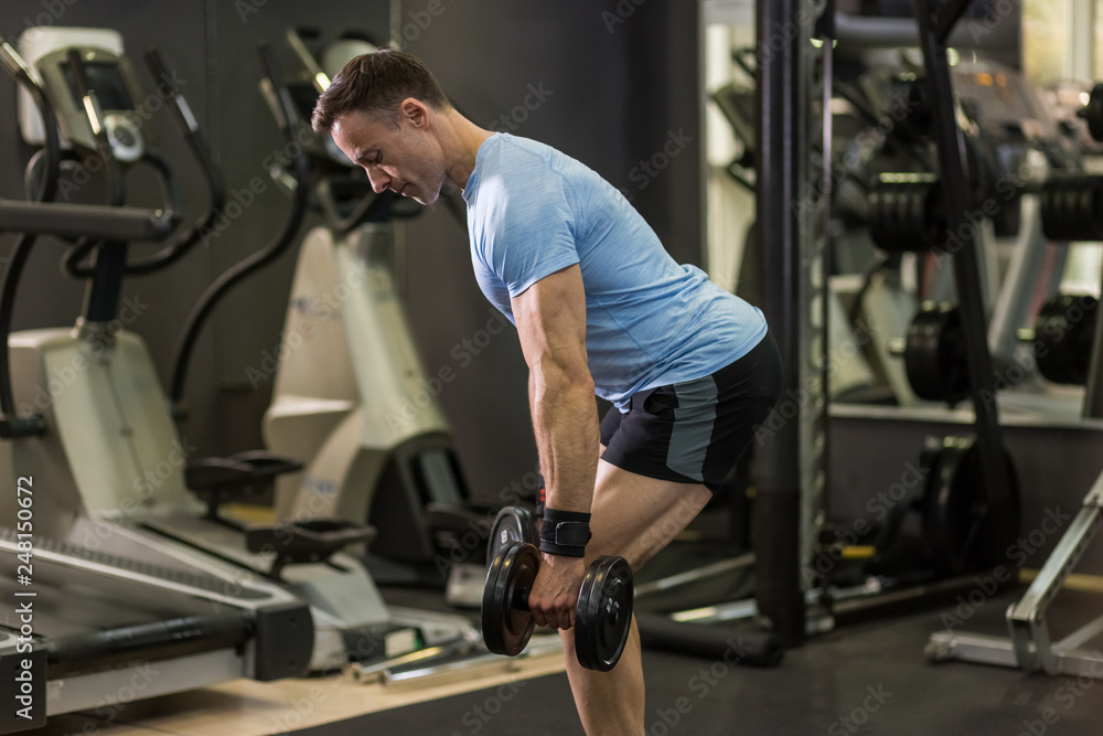 Muscular man pulling heavy dumbbell at the gym. Muscular man pulling heavy dumbbell at the gym.