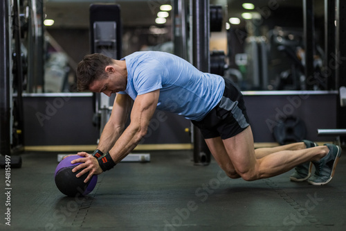 Muscular man practicing plank exercise using a ball at the gym.