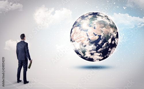 Businessman standing with his back with objects in his hand and looking at the globe  courtesy of NASA  