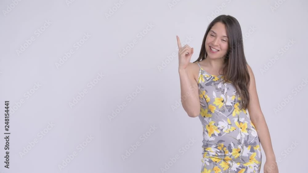 Young happy multi-ethnic tourist woman thinking and pointing up Young happy multi-ethnic tourist woman thinking and pointing up