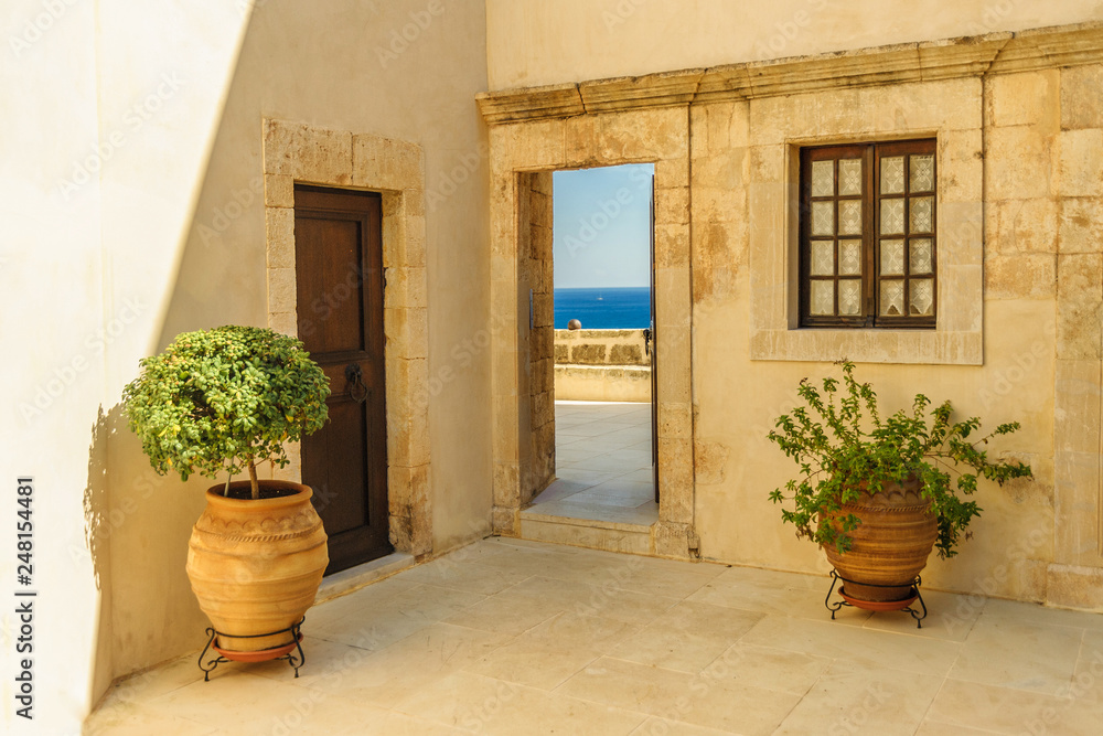 Yellow wall of the monastery with doors, window and flowerpots Yellow wall of the monastery with doors, window and flowerpots