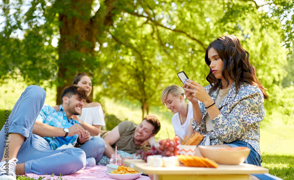 leisure, technology and people concept - woman using smartphone at picnic with friends in summer park leisure, technology and people concept - woman using smartphone at picnic with friends in summer park
