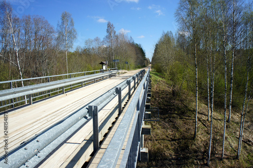 Narrow bridge of metal and wood for crossing the Salaca River in Latvia. © valerijs