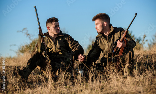 Hunters with rifles relaxing in nature environment. Hunting with friends hobby leisure. Hunters satisfied with catch drink warming beverage. Hunters friends enjoy leisure. Rest for real men concept