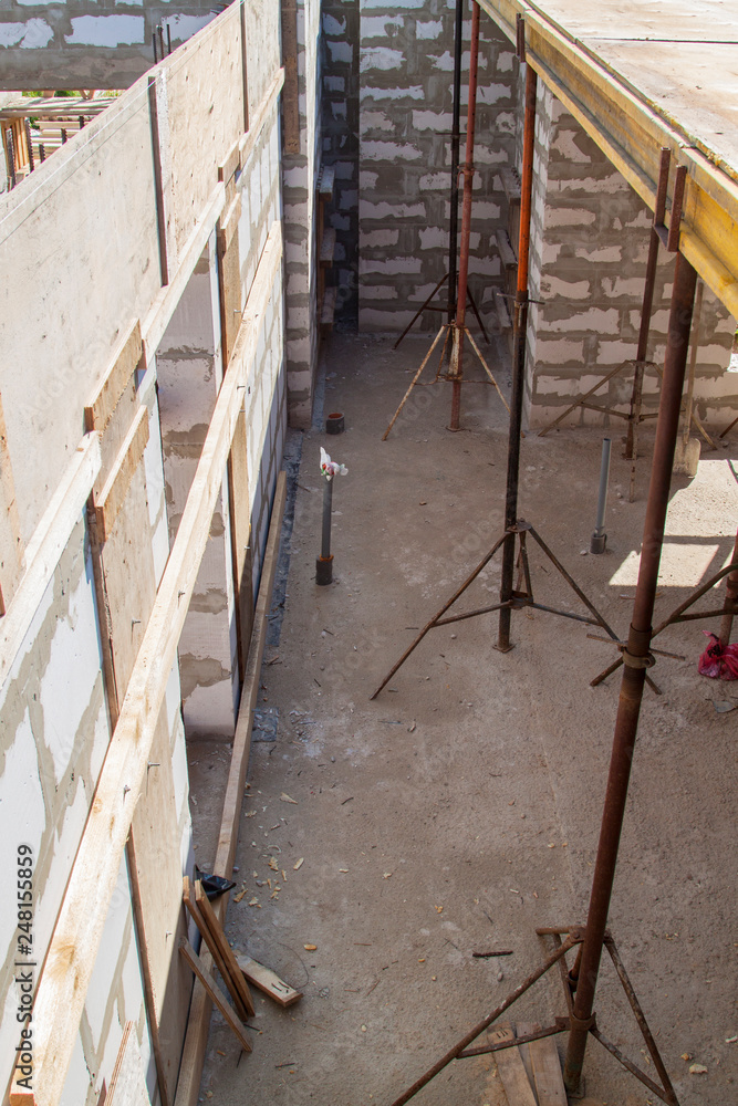 Obraz premium view of the wooden formwork with metal holders, which will be filled with the overlap between the floors in the country house under construction from the foam block