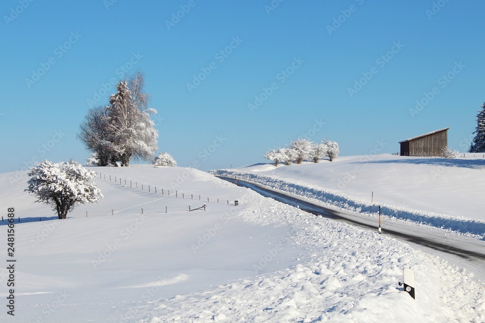 Kurvige Landstraße in verschneiter Winterlandschaft, Allgäu, Bayern
