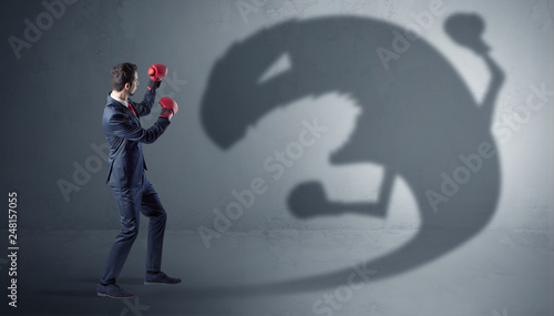 Businessman with boxing glove fighting with a big monster shadow
 photo
