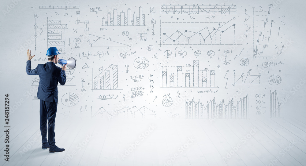 Engineer with construction helmet holding a plan and standing with graphs, charts and reports on the background Engineer with construction helmet holding a plan and standing with graphs, charts and reports on the background