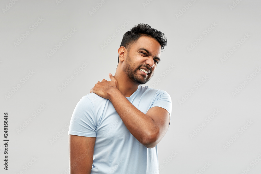 health problem and people concept - unhealthy indian man suffering from neck pain over grey background health problem and people concept - unhealthy indian man suffering from neck pain over grey background