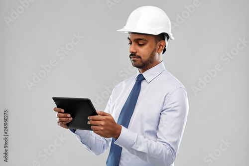 architecture, technology, construction business and building - indian architect or businessman in helmet with tablet computer over grey background