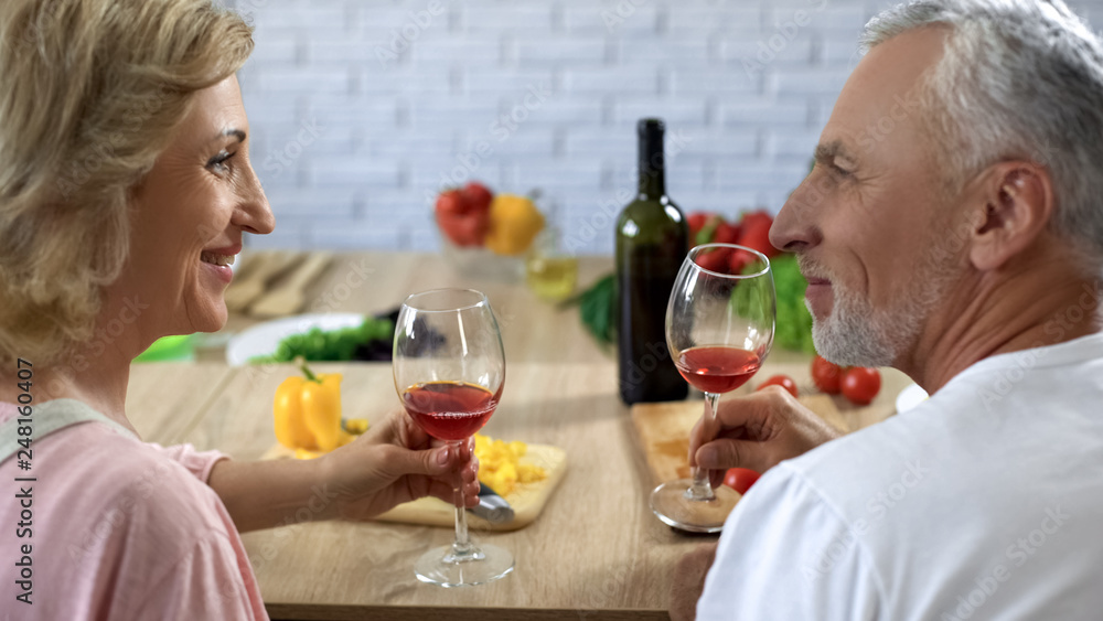 Romantic retired couple with wine glasses looking each other with love, aperitif Romantic retired couple with wine glasses looking each other with love, aperitif