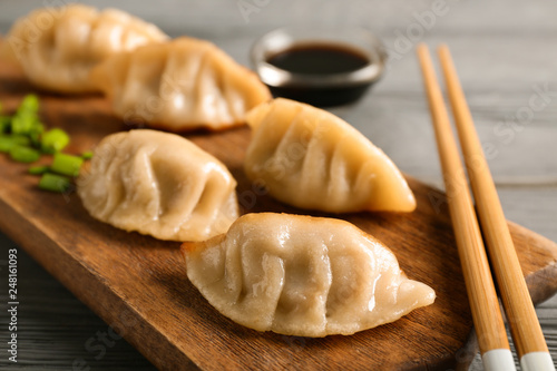 Board with tasty Japanese gyoza on wooden table, closeup