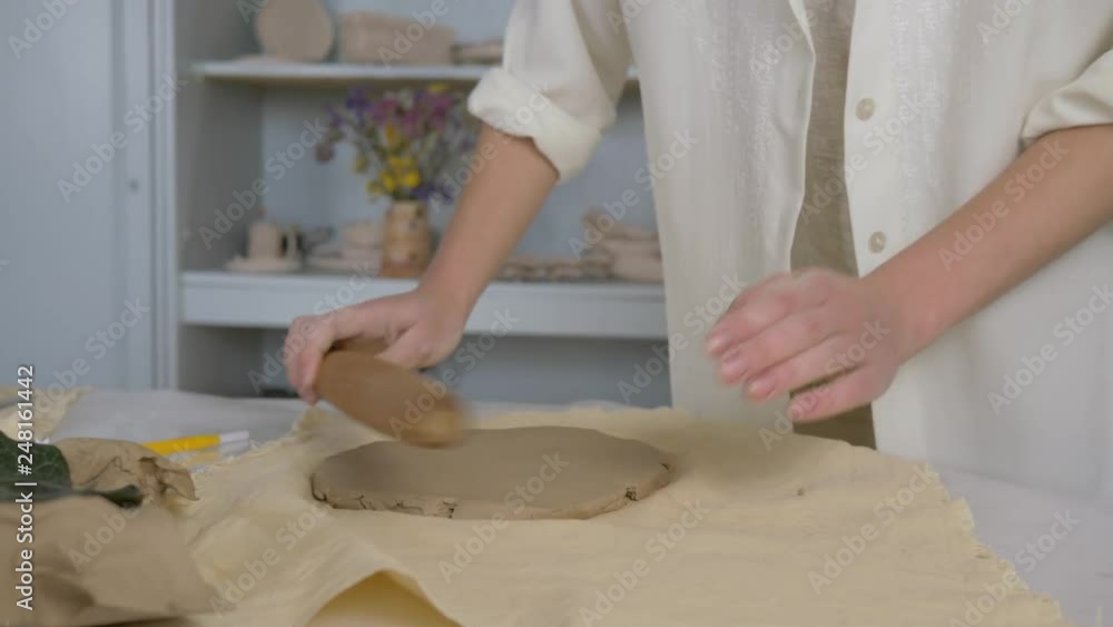 potter master rolls clay on table using rolling pin for making ceramic tableware at crafting studio close-up potter master rolls clay on table using rolling pin for making ceramic tableware at crafting studio close-up