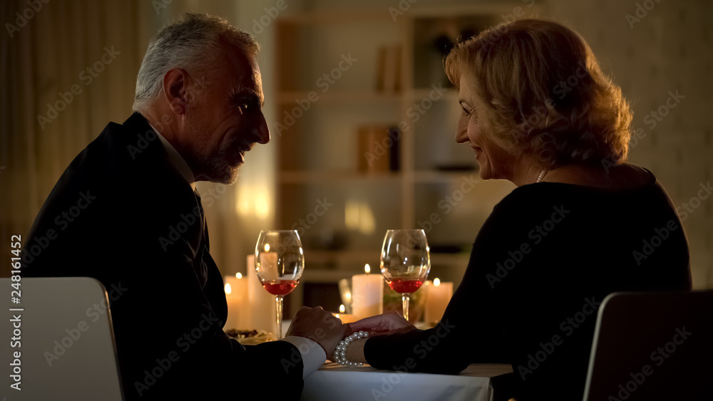 Handsome man and woman holding hands, celebrating anniversary date together Handsome man and woman holding hands, celebrating anniversary date together