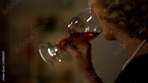 Elegant aged lady drinking red wine, romantic date in restaurant, celebration