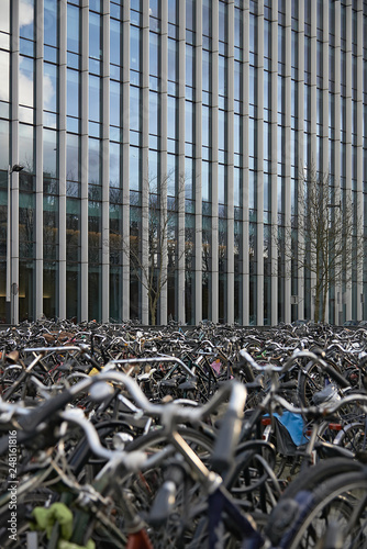 Lots of bicycles parked in front of a modern office business building photo