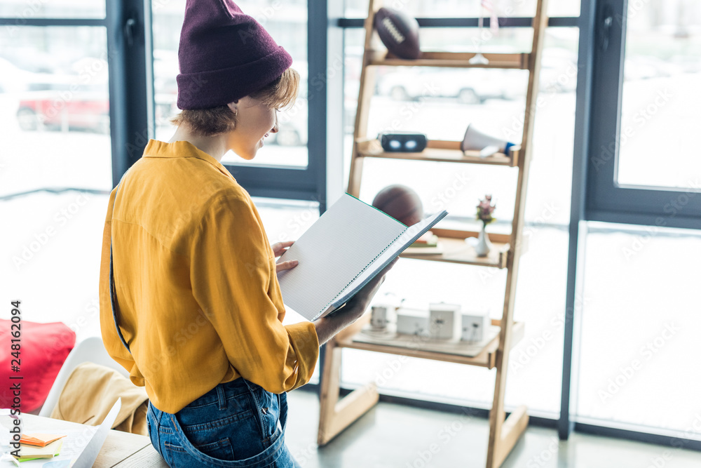 female designer holding notebook in loft office with copy space