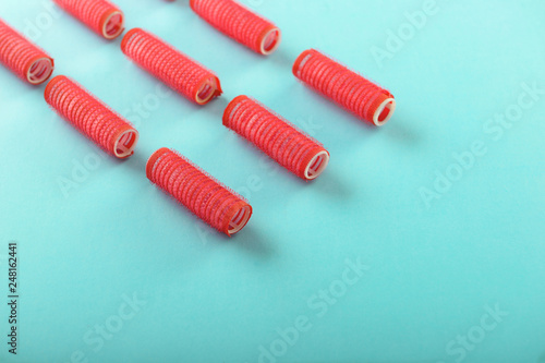 Hair curlers on color background