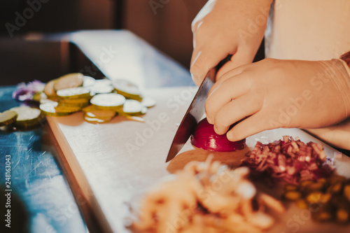 Chef starts cutting onion with a knife on the board