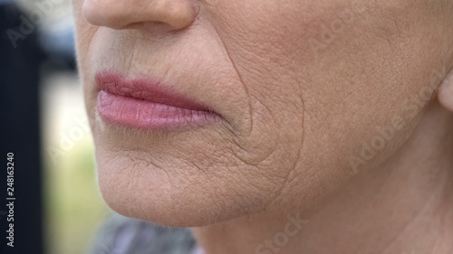 Wrinkled face of pensioner female, anti-age cream, skincare and cosmetology