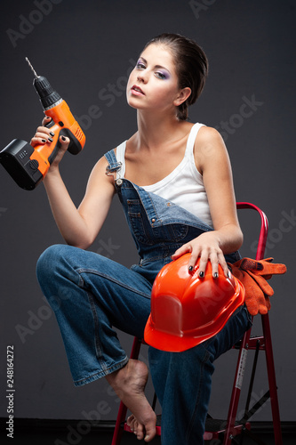 Young builder woman with a drill.