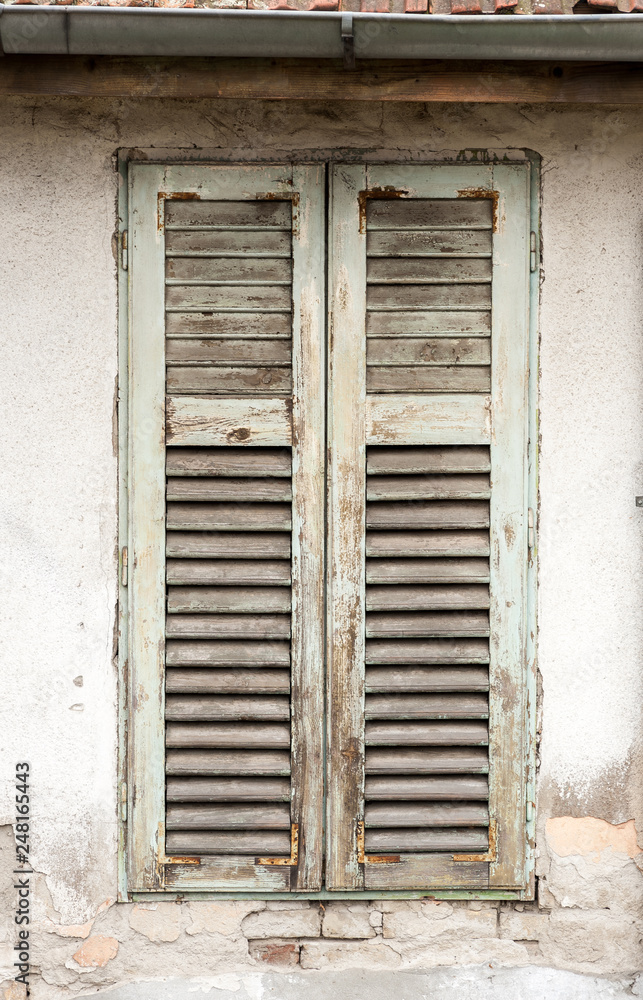 Fototapeta premium Old damaged wooden curtains or shades on abandoned house window vertical image