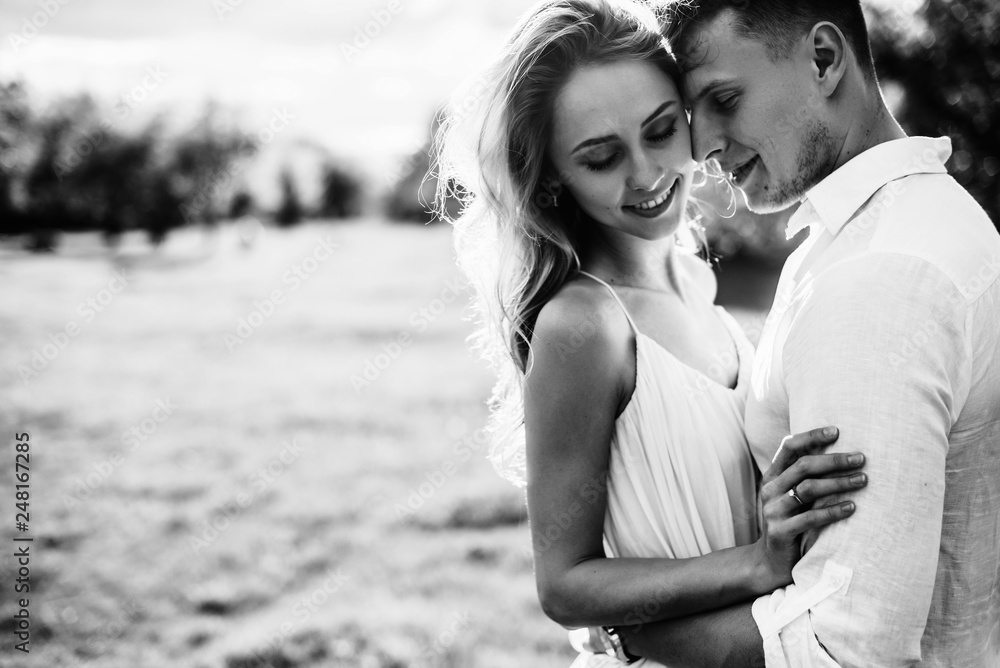 Black and white photo on which he guy hugs his beloved girlfriend. A loving couple spends time outside the city. Love story Black and white photo on which he guy hugs his beloved girlfriend. A loving couple spends time outside the city. Love story