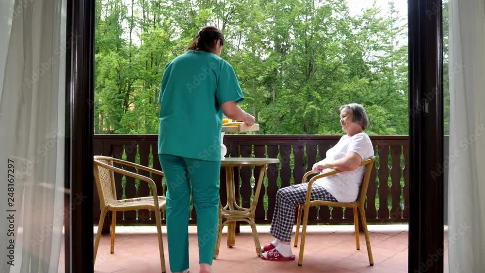 Pan of smiling young nurse serving breakfast to happy senior woman at nursing home. Slow motion 4k Pan of smiling young nurse serving breakfast to happy senior woman at nursing home. Slow motion 4k