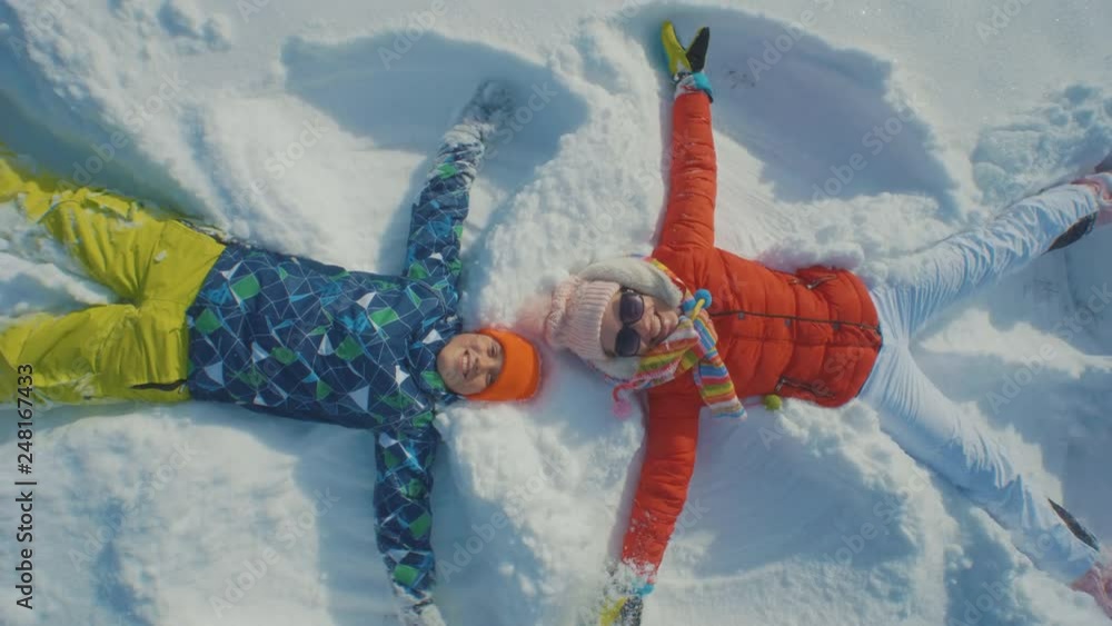 Mother and son making angels in the snow and having fun