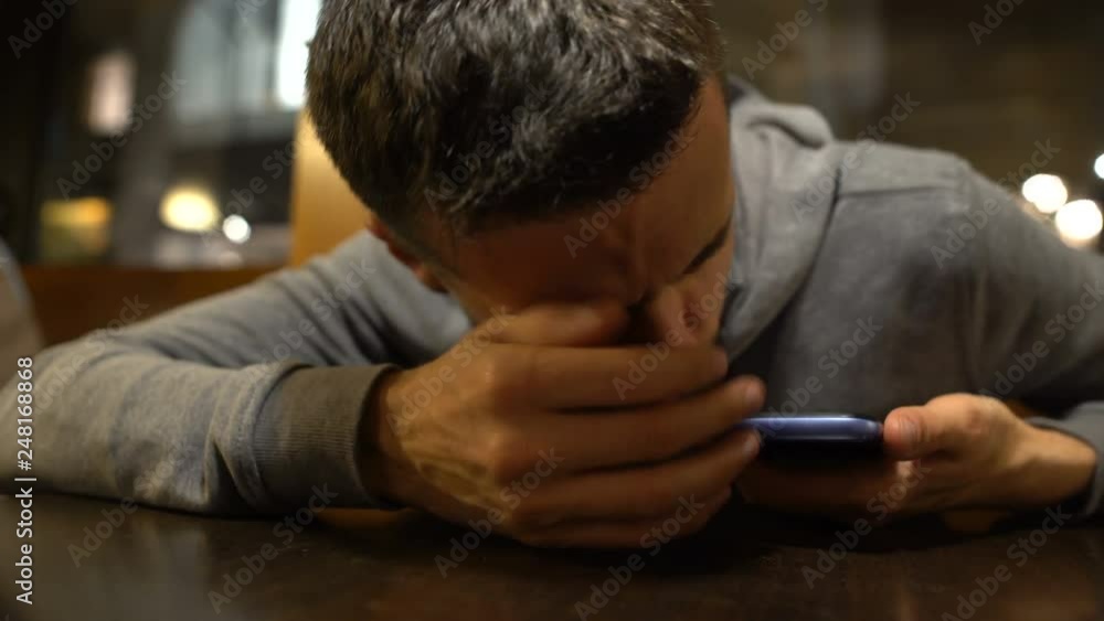 Drunk man waking up on table in restaurant after party, calling taxi, hangover Drunk man waking up on table in restaurant after party, calling taxi, hangover