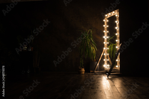 Billede på lærred Toilet mirror stands on a wooden floor with light bulbs for lighting