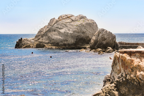 People swim around the rocks.